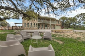 A stone building with a balcony, surrounded by grass and trees. - Grasslands: Pool+Hot-Tub+Views on 290 Wine Trail! (Johnson City)