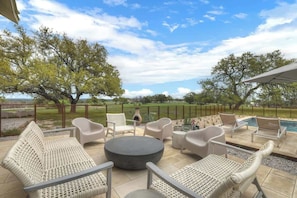 Un patio al aire libre con muebles de mimbre, una mesa redonda y una piscina al fondo.