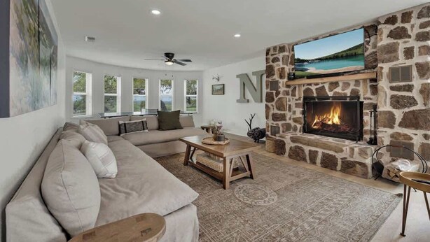 Un salón con chimenea de piedra, un ventanal grande y un sofá.