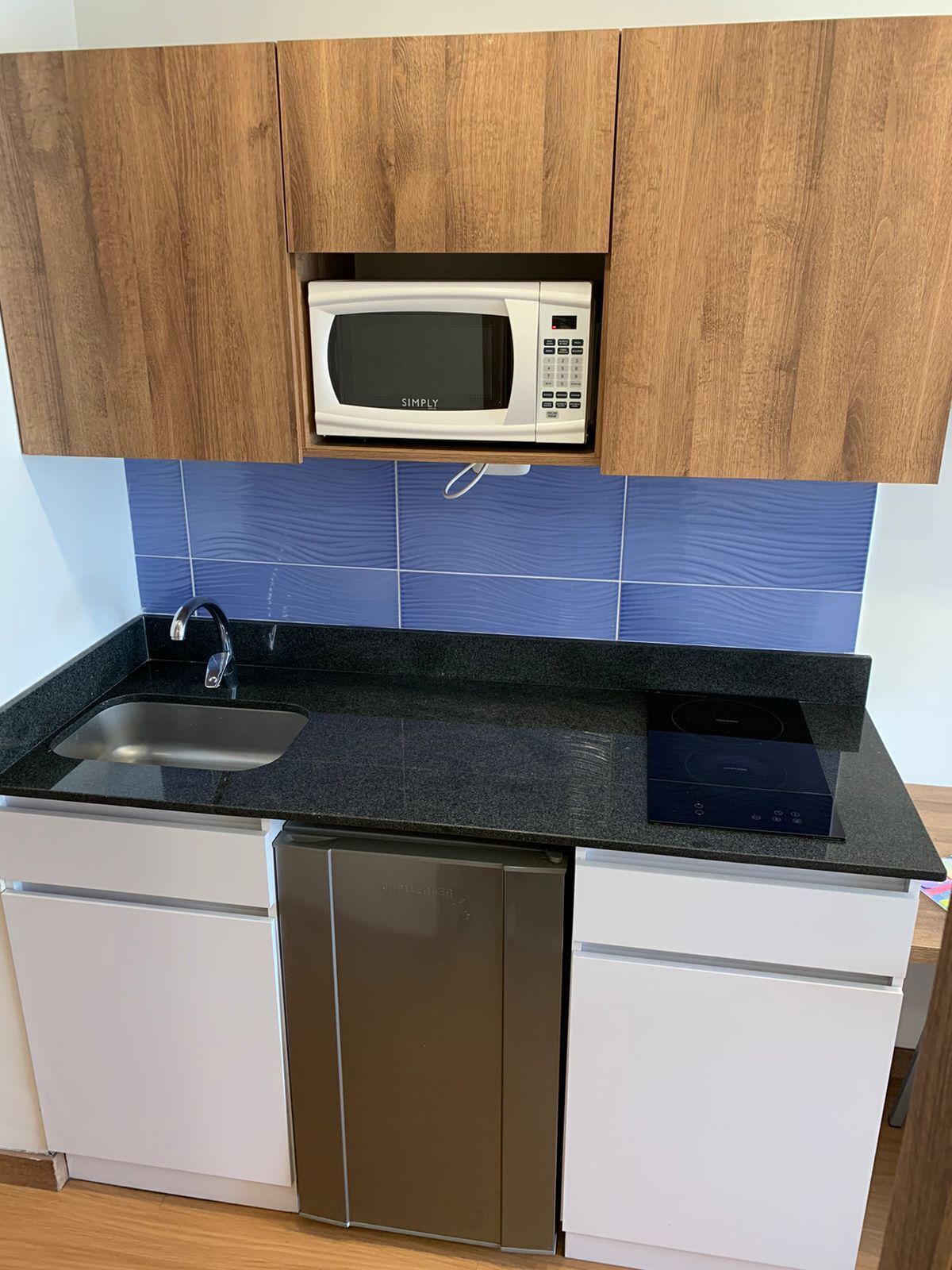 Una cocina con armarios de madera, microondas, lavaplatos y fregadero.