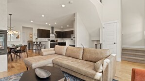 Una sala de estar moderna con un sofá modular, un comedor y una cocina.