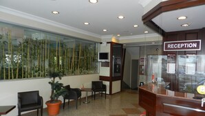 A reception area with a reception desk, seating, a large window with a view of bamboo, and a sign indicating the reception. - SEFA 2 BUTİK HOTEL (Corlu)