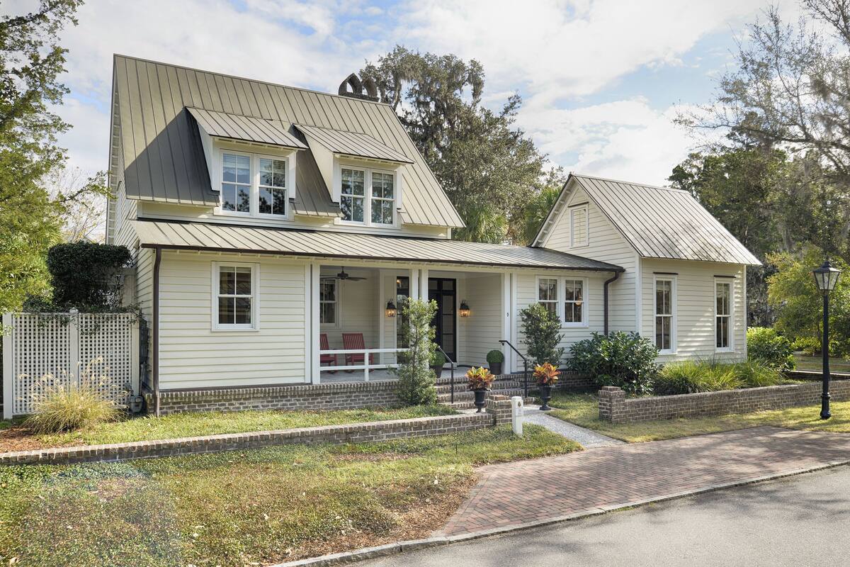 Een tweelaags huis met een veranda, een fundering van baksteen en een metalen dak.