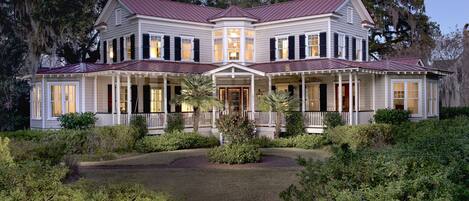 A large, two-story house with a symmetrical facade, multiple windows, and a central entrance.