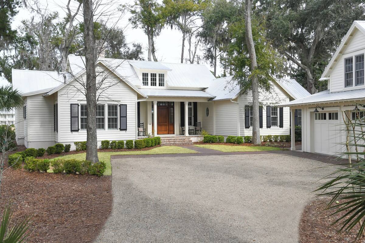 Een twee verdiepingen tellend huis met een veranda, een garage en een oprit.