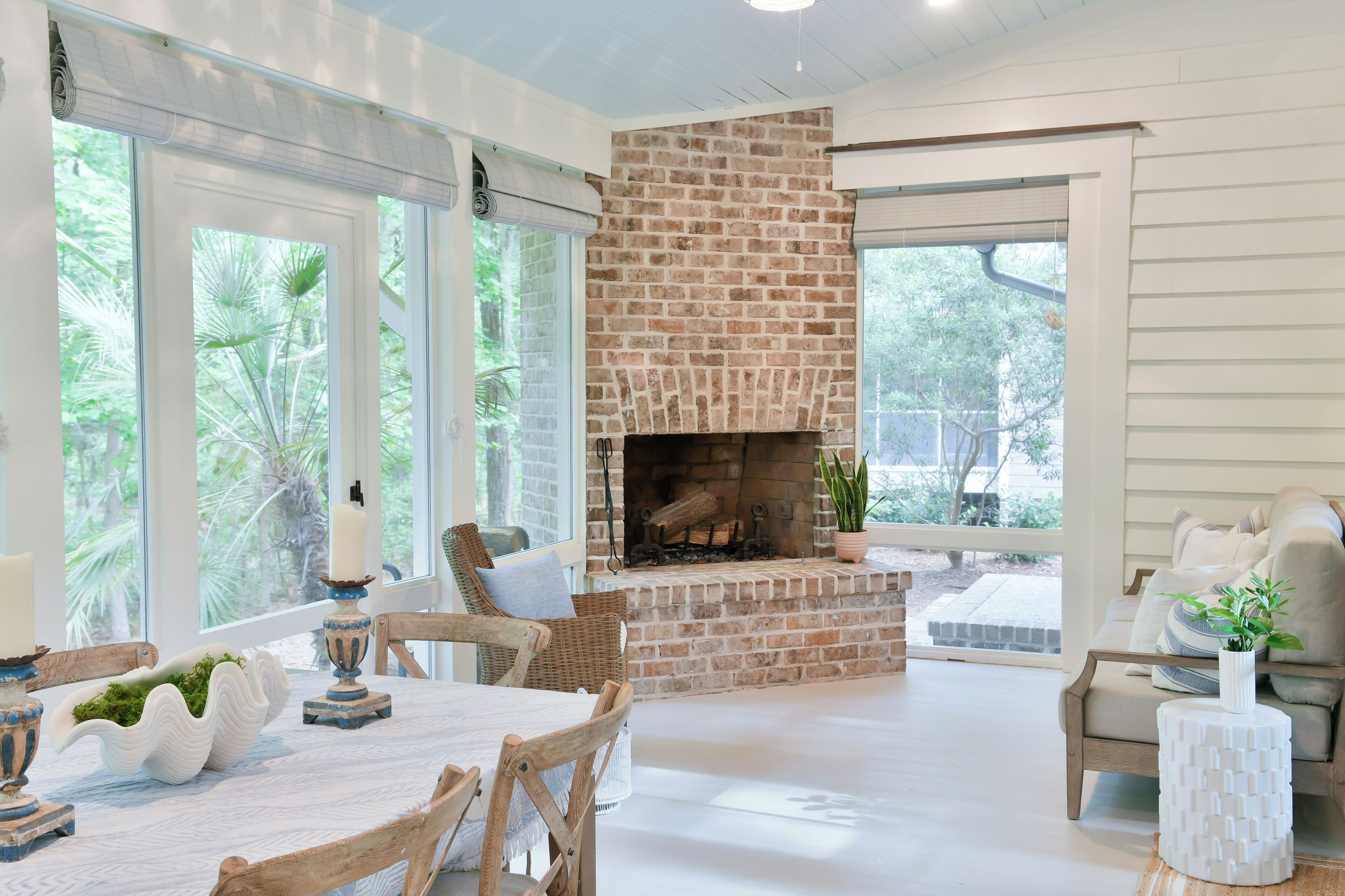 A spacious living area with a brick fireplace, large windows, and a comfortable seating arrangement.