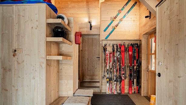 A wooden ski storage room with skis and ski equipment.