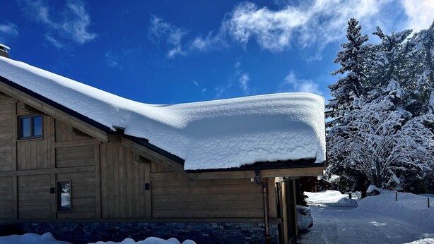 A wooden cabin with a snow-covered roof and a stone foundation. - Chalet Familial vue Mont Blanc à 100m des Pistes de ski (Taninges)