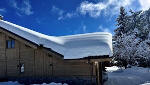 A wooden cabin with a snow-covered roof and a stone foundation.