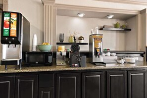 A hotel kitchen with a coffee machine, microwave, waffle maker, and a juice dispenser. - Quality Inn & Suites Weatherford, TX (Weatherford)