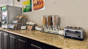 A breakfast bar with a waffle maker, cereal dispensers, and a toaster. - Quality Inn & Suites Weatherford, TX (Weatherford)