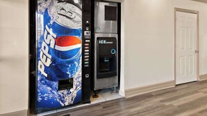 An ice dispenser with a Pepsi logo, a door, and a wooden floor. - Quality Inn & Suites Weatherford, TX (Weatherford)