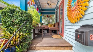 A porch with a wooden bench and table, a mailbox, and a decorative sun on the wall.