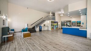 Un vestíbulo amplio con piso de madera, una escalera, zona de estar y un mostrador de recepción.