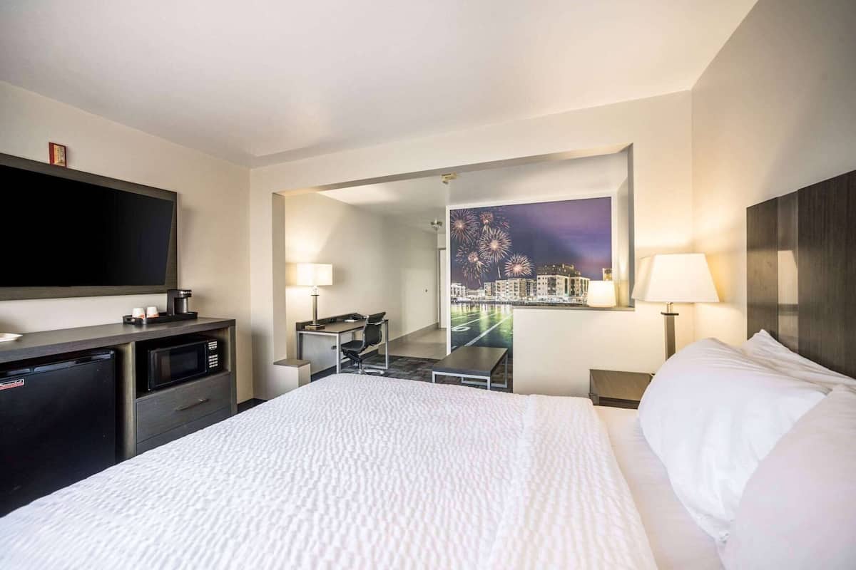 Une chambre d’hôtel équipée d’un lit, d’un bureau, d’une chaise, d’un téléviseur à écran plat, d’une machine à café et d’un miroir.
