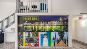 Un pasillo con un gran mural de un paisaje urbano y un campo de fútbol, una escalera y una señal de salida.