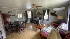 A living room with a dining table, chairs, a sofa, and a ceiling fan. - COZY CABIN (Mount Ida)