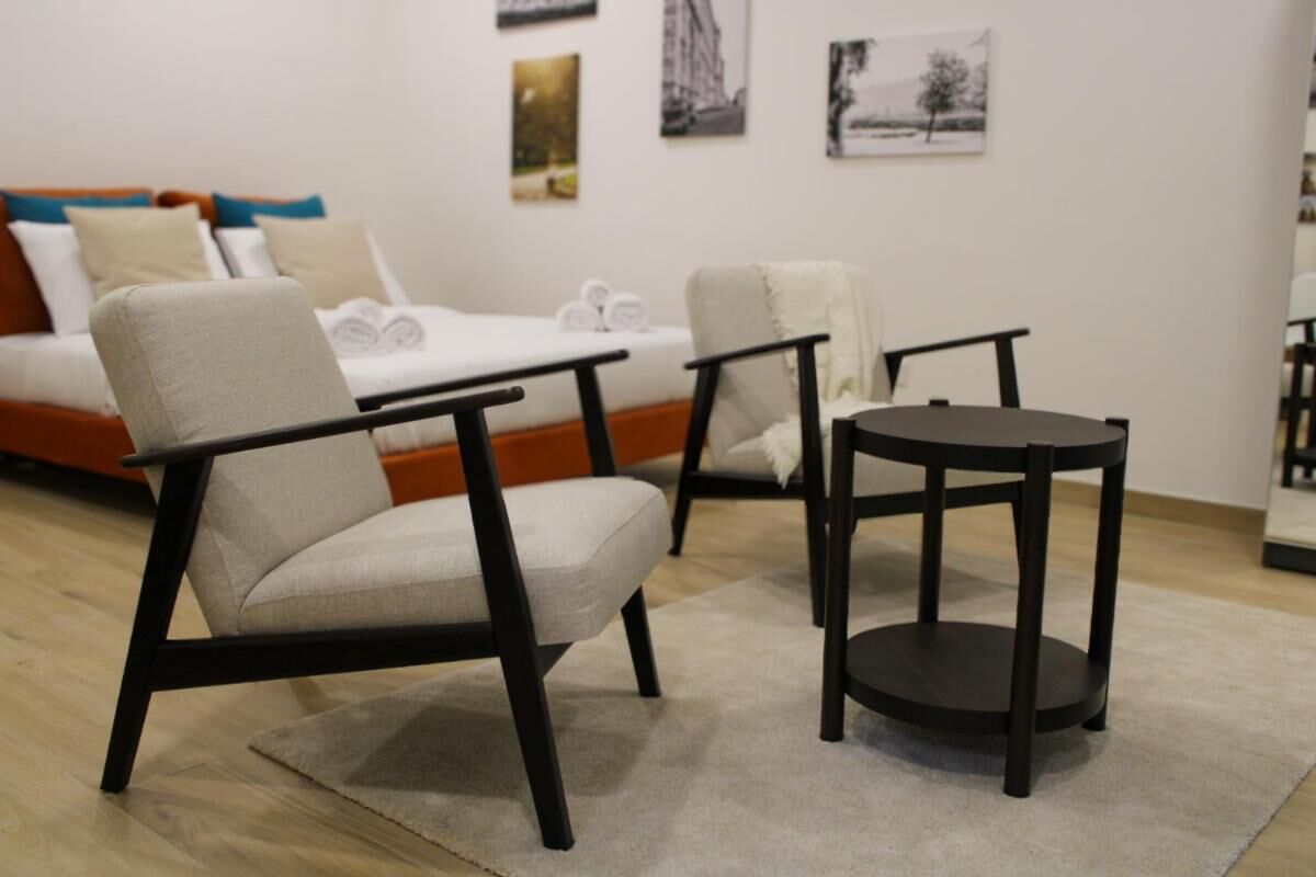 Une chambre d’hôtel moderne, équipée d’un canapé, de deux fauteuils, d’une petite table et d’œuvres d’art accrochées aux murs.