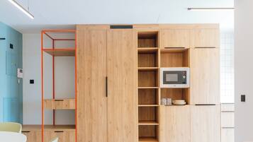 A modern kitchen with wooden cabinets, a microwave, and a small dining area with a table and chairs.