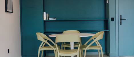 Un petit coin repas comprenant une table et des chaises, un mur de couleur turquoise et une porte.