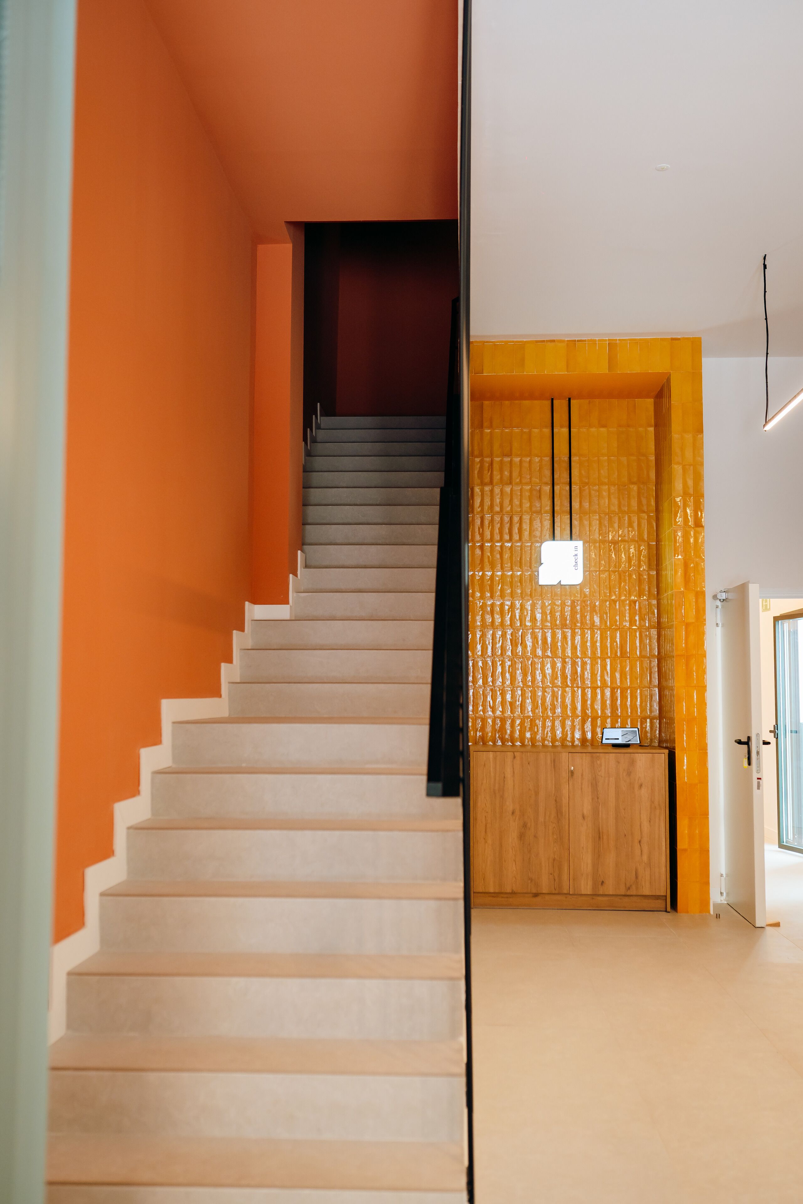 A staircase with a wooden finish, leading to a room with a wooden door and a small table.
