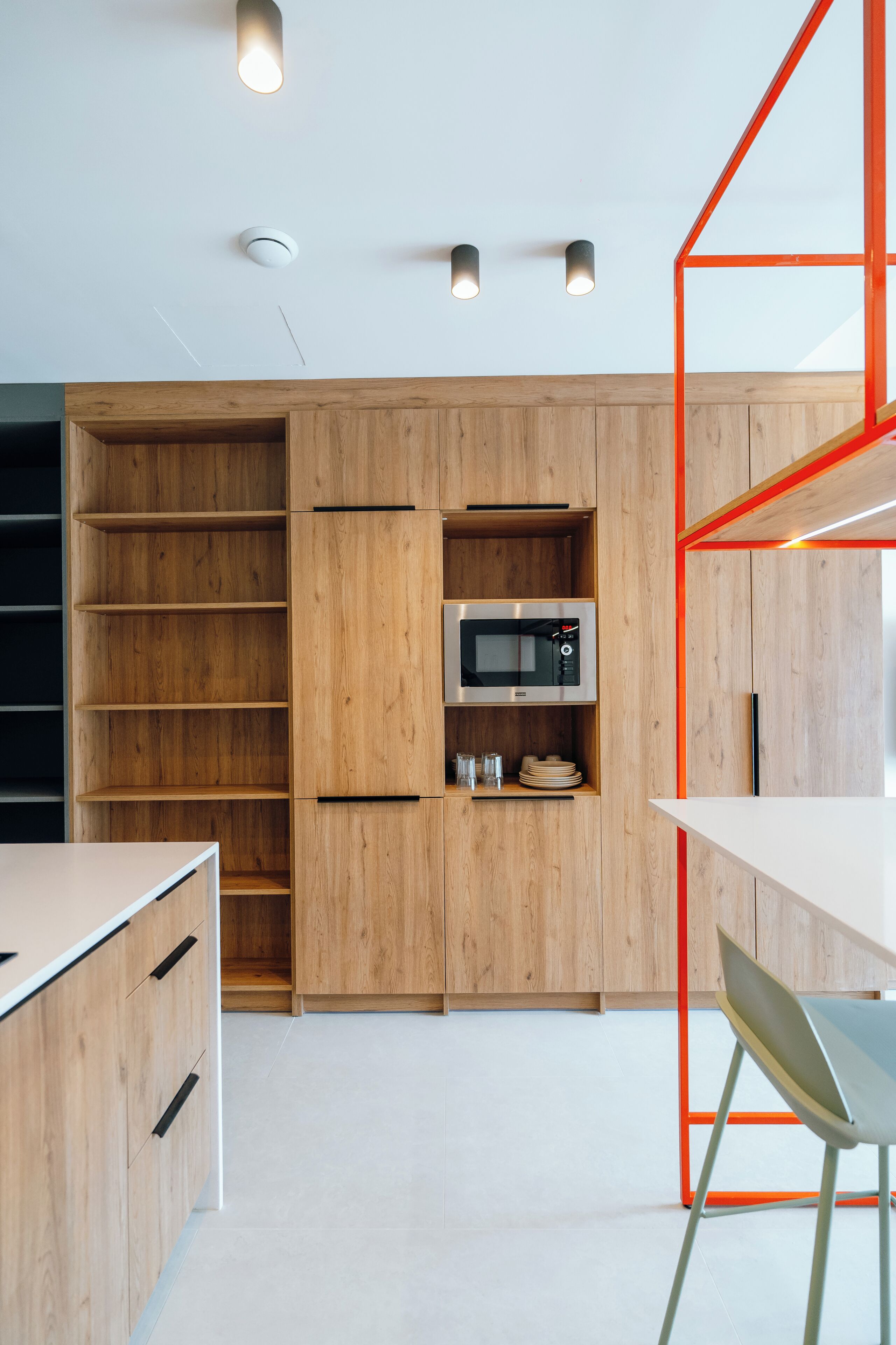 A modern kitchen with wooden cabinets, a built-in microwave, and a white countertop.