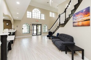 A spacious interior with a staircase, a sofa, and a painting on the wall. - Surestay Studio by Best Western Conroe Downtown (Conroe)