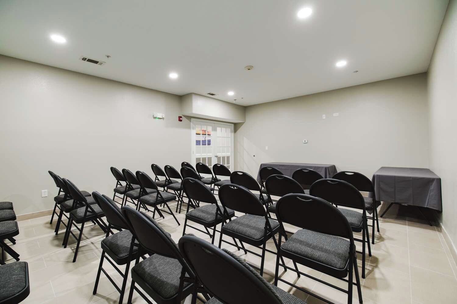 A conference room with rows of chairs, a table, and a door with a poster.