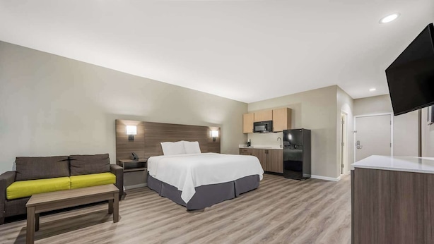Une chambre d’hôtel équipée d’un lit, d’un bureau, d’un canapé, d’une kitchenette et d’un téléviseur à écran plat.