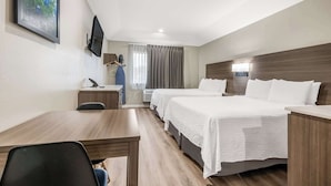 Une chambre d’hôtel avec deux lits, un bureau, une chaise, une télévision et une fenêtre avec des rideaux.