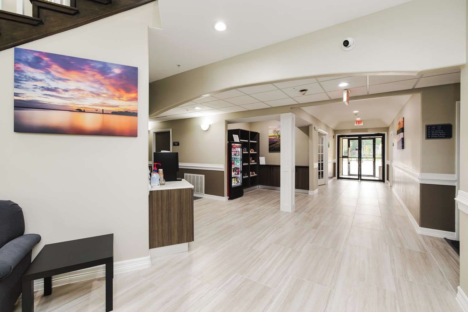 A hotel lobby with a reception desk, a vending machine, and a wall-mounted television.