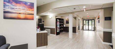 A hotel lobby with a reception desk, a vending machine, and a wall-mounted television.