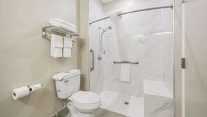Une salle de bain moderne équipée de toilettes, d’une douche et d’un porte-serviettes.