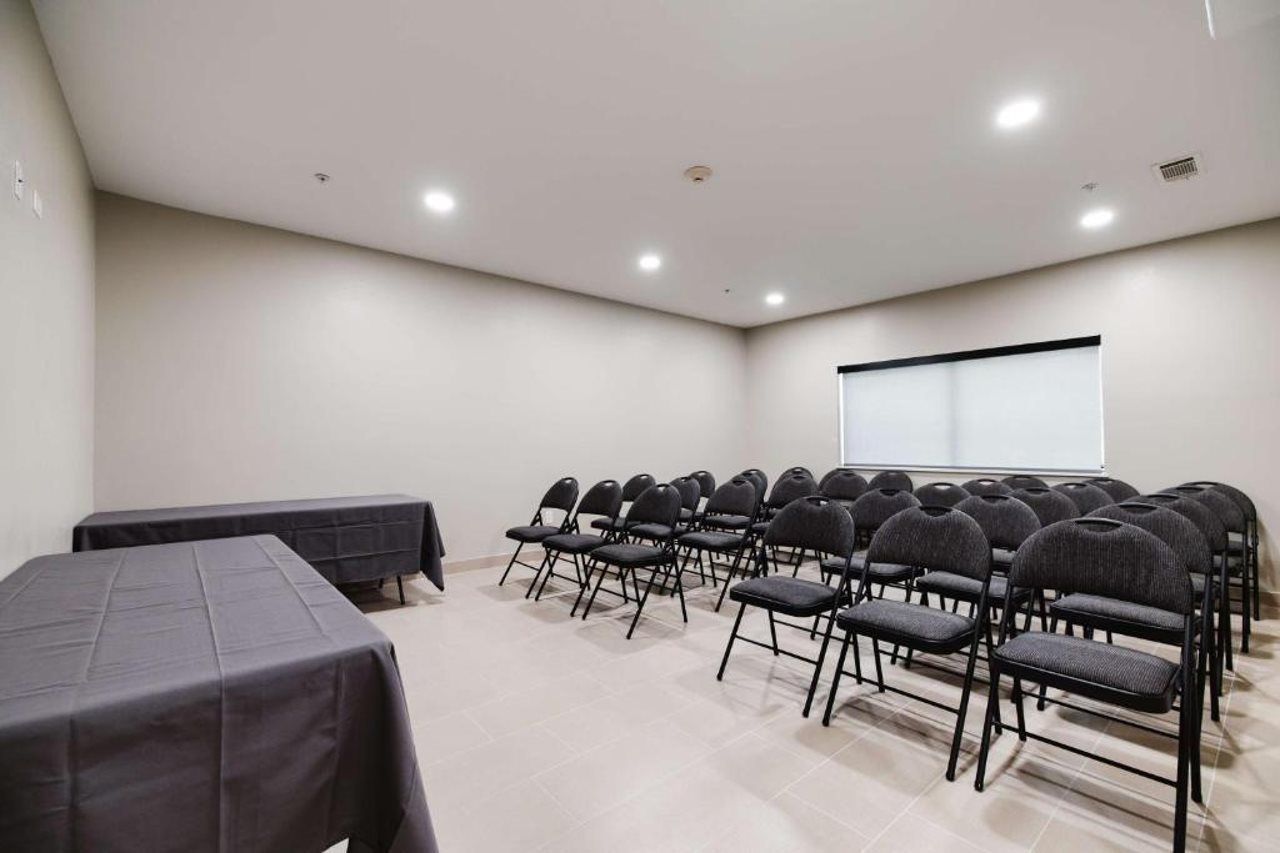 A conference room with rows of chairs and tables, a projector screen, and a whiteboard.