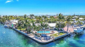 Marina com barcos atracados, piscina e palmeiras.