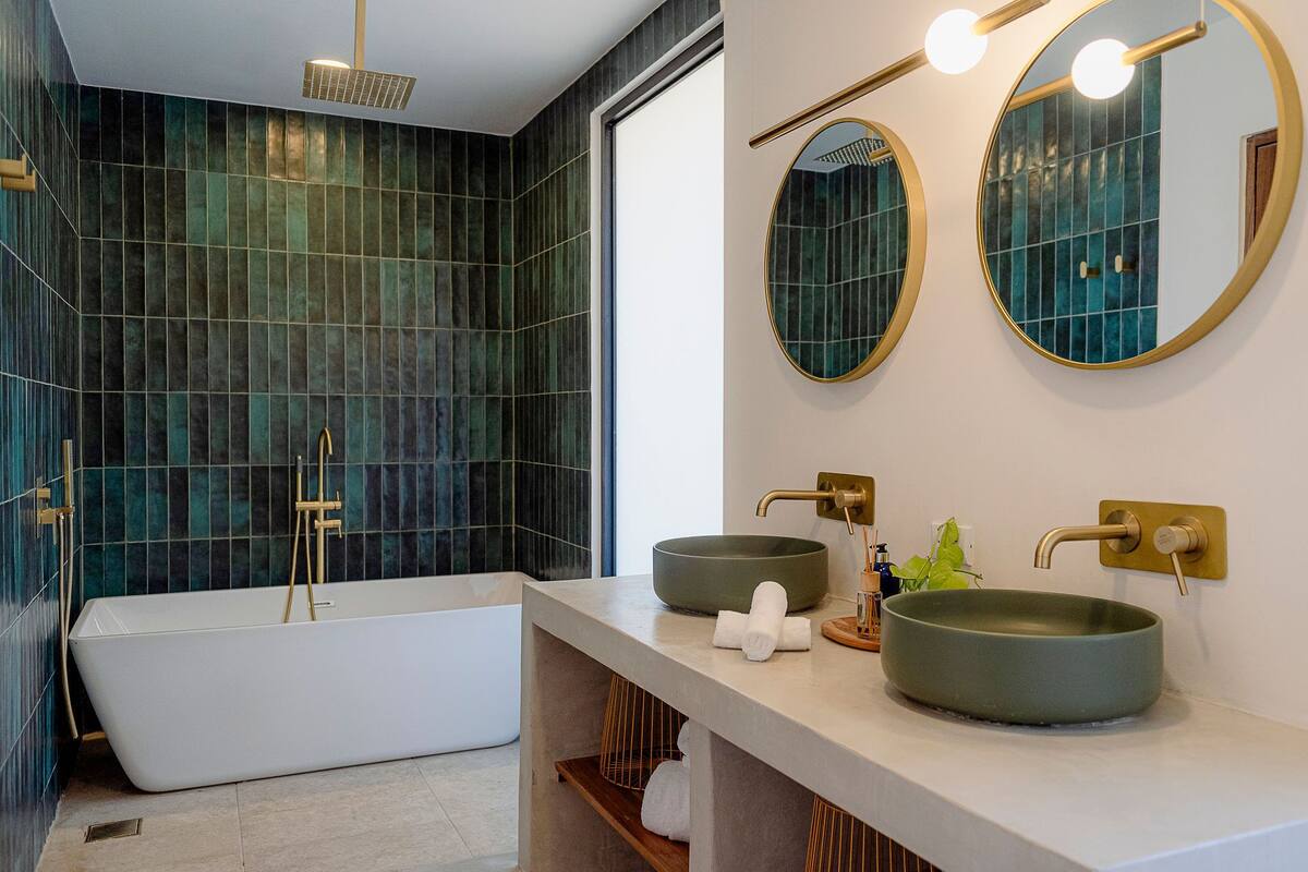 A modern bathroom with a freestanding bathtub, two round mirrors, and a large sink with a vessel basin.