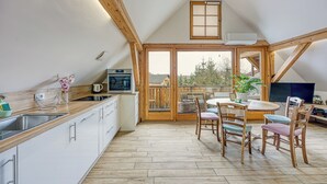 Et moderne køkken med træbordplade, hvide skabe og et spiseområde med træstole og et bord.