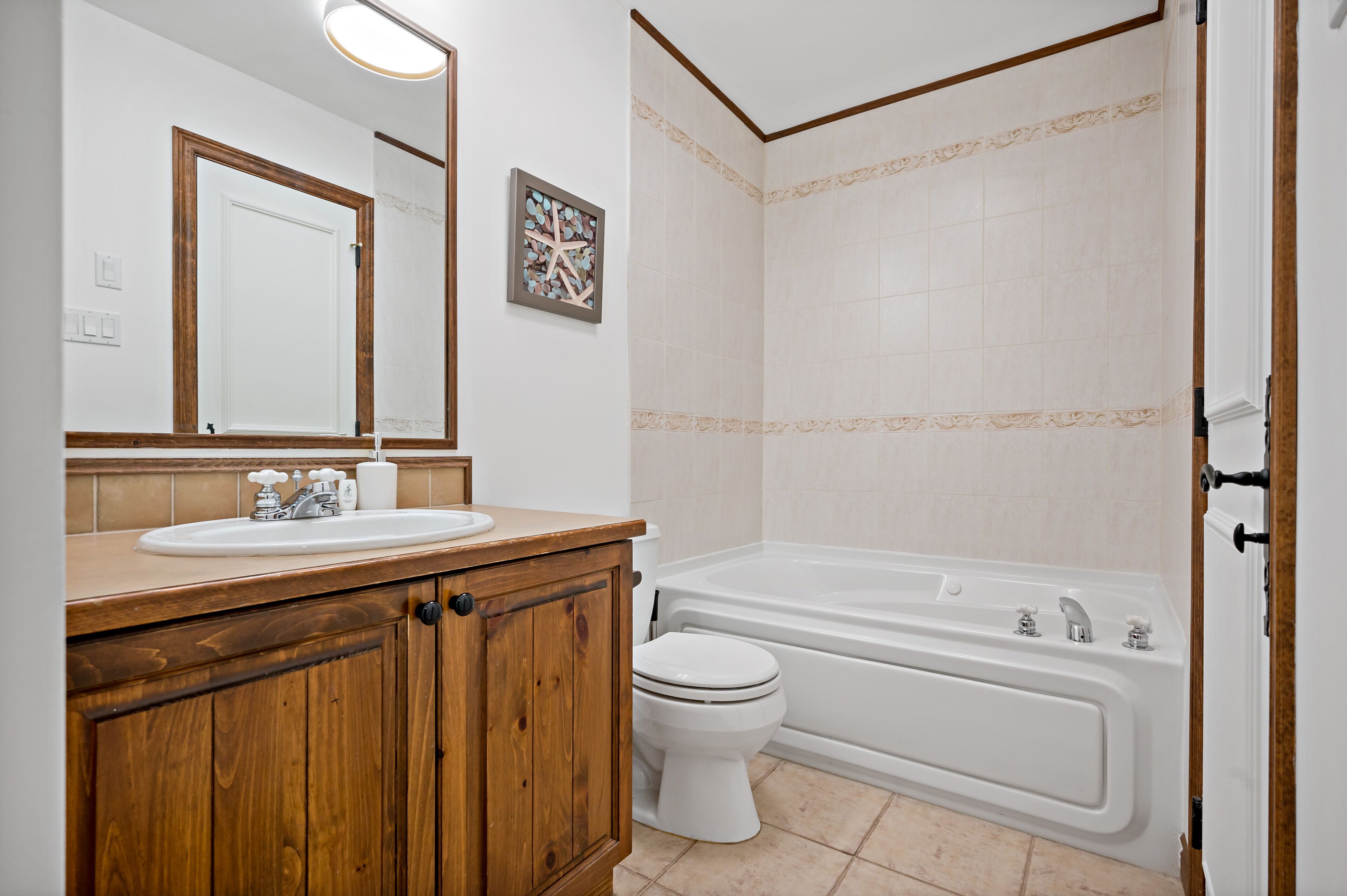 A bathroom with a wooden vanity, a sink, a toilet, and a bathtub.
