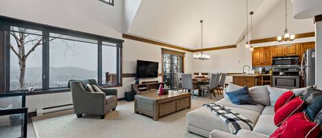 A spacious living room with a large window, a fireplace, and a dining area.