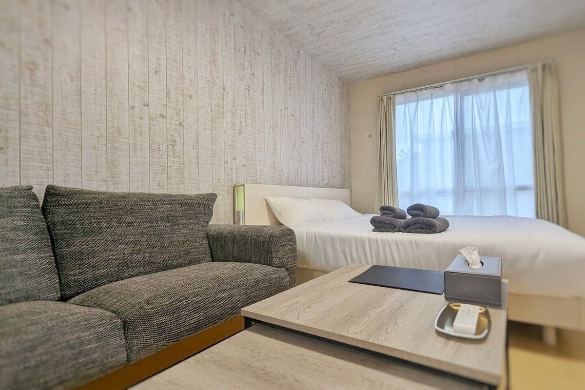 Ein Hotelzimmer mit einer Couch, einem Bett, einem Nachttisch und einem Fenster mit Vorhängen.