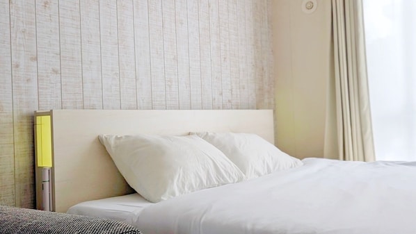 A hotel room with a bed, white bedding, a headboard, and a wall with a textured pattern. - Yonaguni-mumbu Airport Hotel (Yonaguni)