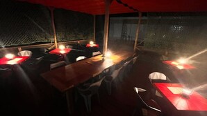 A dimly lit restaurant with tables and chairs under a red canopy. - Yonaguni-mumbu Airport Hotel (Yonaguni)