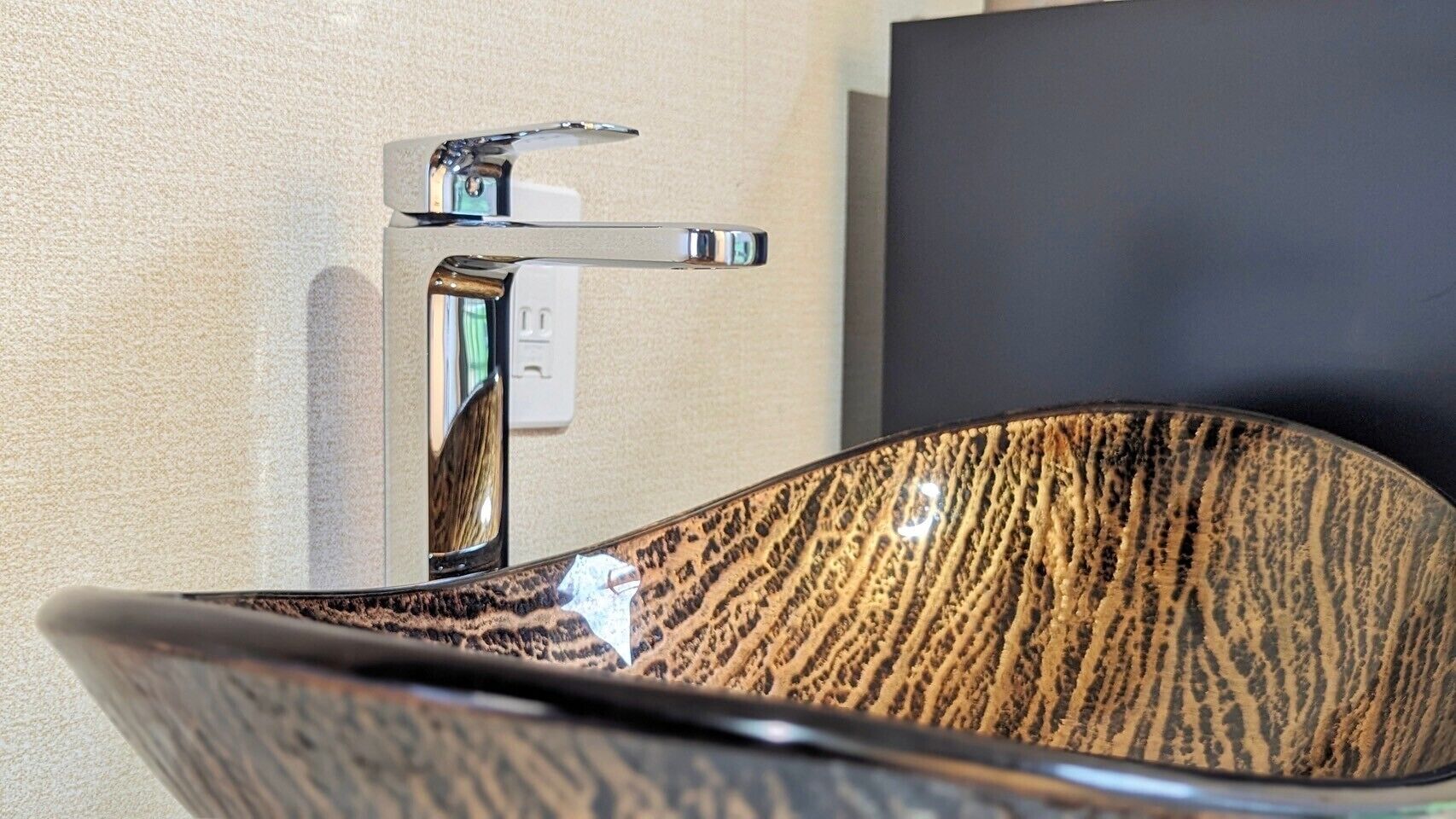 A modern bathroom with a wooden-textured sink and a chrome faucet.