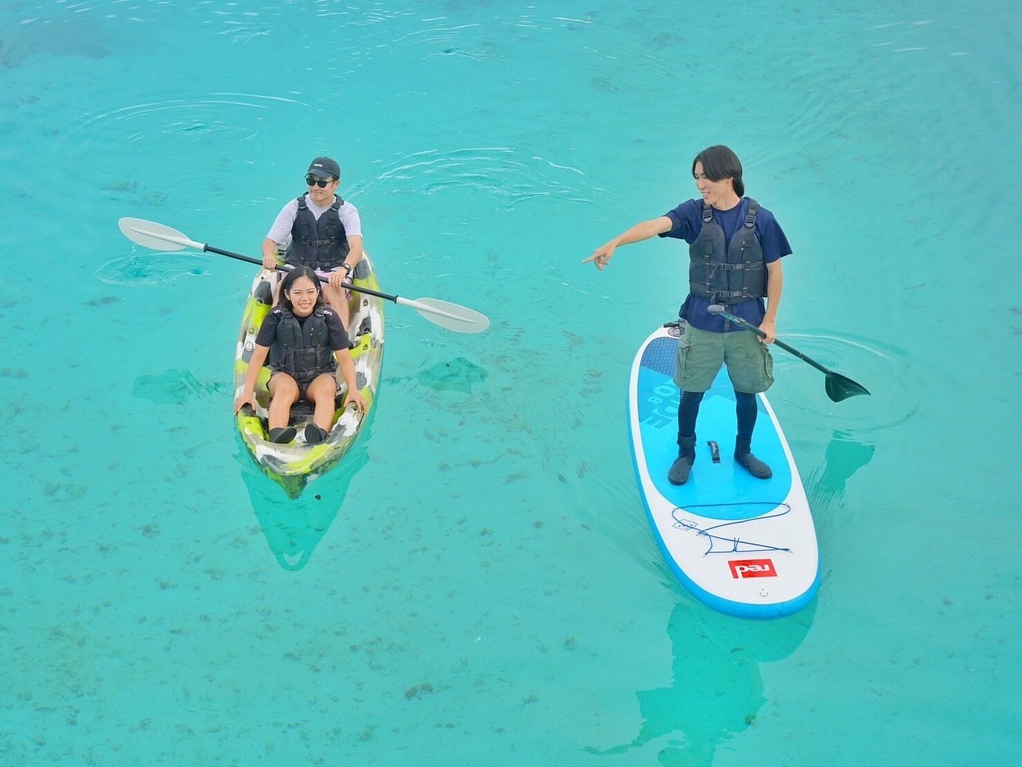 Dos personas en tablas de remo en aguas cristalinas.
