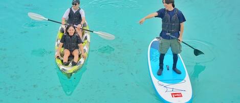 Dos personas en tablas de remo en aguas cristalinas.