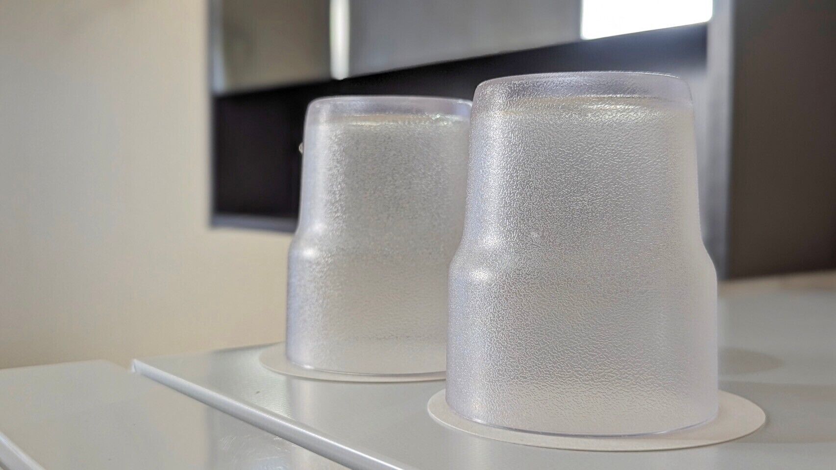 Two frosted glass tumblers on a white surface.