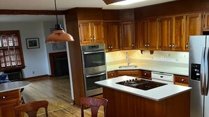 Une cuisine moderne avec des meubles en bois, un îlot central et un coin repas comprenant une table ronde et des chaises.
