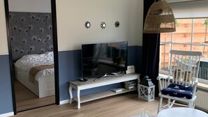 Una habitación moderna con una cama, un televisor, una mesita y una silla.