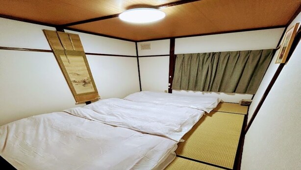 A small, single-bed room with a tatami mat floor and a traditional Japanese shoji screen. - Minpaku Ota Building 3 (Otaru)
