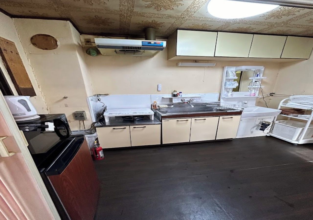 A kitchen with a microwave, stove, and sink. There is a fire extinguisher on the floor.
